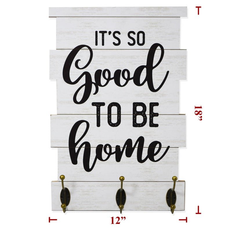 "It's So Good To Be Home" wood sign with a white background and black writing with three metal hooks